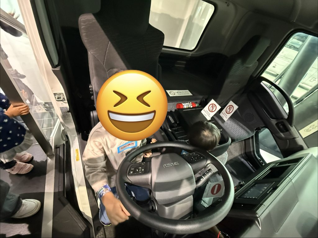 いすゞプラザのトラック運転席でハンドルを握る子ども